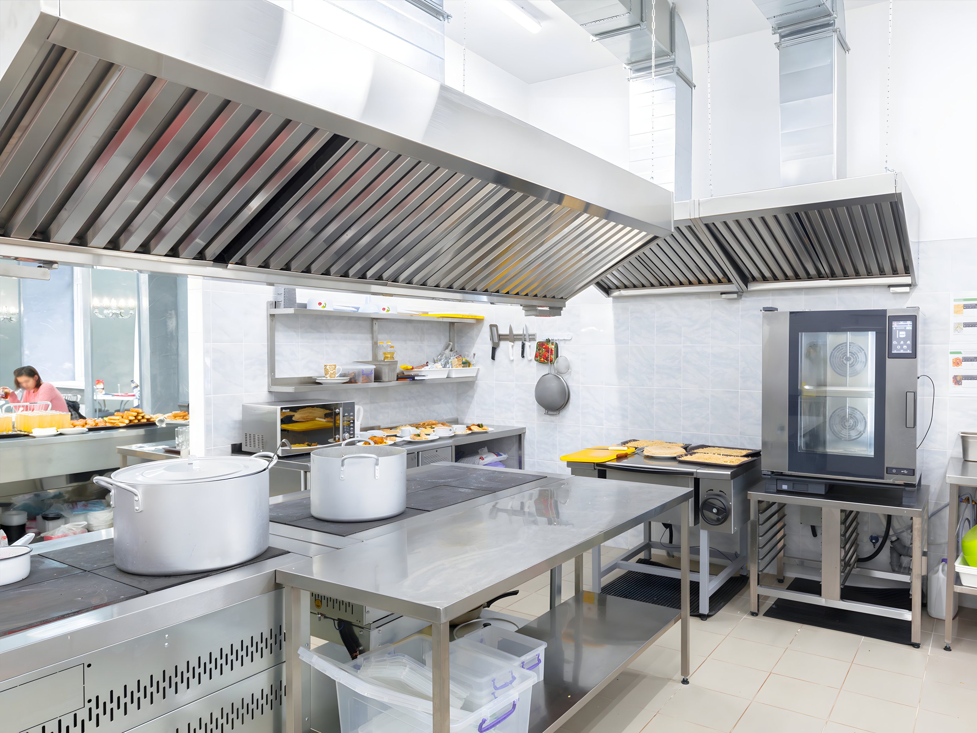 The long exhaust hood line over a commercial kitchen cook line